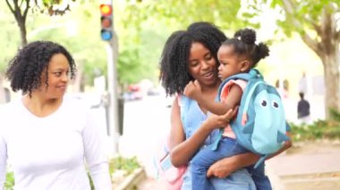 Afrikalı bir anne parkta büyükannesiyle yürürken kucağında bir kız taşıyor.