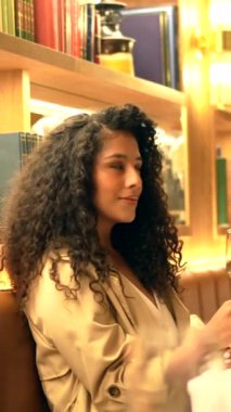 Güzel, şık, Latin bir kadının bir restoranda dikkati dağınık bir şekilde oturup tek başına bakışının yan görüntüsü.