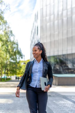 Şehirde dizüstü bilgisayar ve el çantasıyla gezen Latin bir iş kadınının fotokopi alanı olan dikey fotoğraf.
