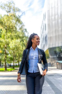 Şehirde dolaşan şık bir Latin iş kadınının dikey fotoğrafı.