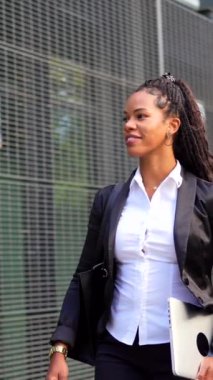 Emlakçı, elinde dizüstü bilgisayarla dışarıda yürüyen Latin bir kadın.