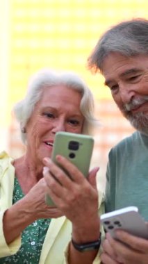 Kıdemli gülümseyen kadın şehirdeki kıdemli ortağa mobil ekranı gösteriyor.