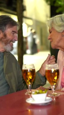 Madrid, İspanya 'da bira ve İspanyol mezelerinin keyfini çıkaran yaşlı bir çiftin dikey videosu.