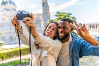 Çok ırklı çift, parkta aynasız fotoğraf makinesiyle selfie çekerken başarılı oluyor.