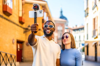 Şehirde cep telefonu ve mikrofonla yayın yapan çok ırklı bir çift.