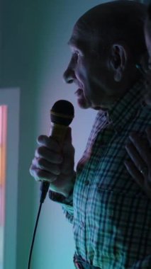 Son sınıf öğrencisi mikrofonla şarkı söylüyor. Duyusal bir odada. Hemşirenin yanında neon ışıkları var.