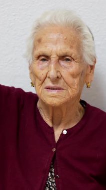Yaşlı kadın geriatri bölümünde sandalyede otururken spor yapmak için süspansiyon metalik halkalar kullanıyor.