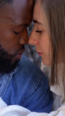 Güzel bir melez çiftin yakınına. Gülleri ovuşturup parkta kucaklaşan genç bir çift.