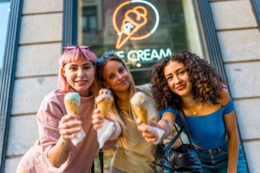 Three beauty different woman holding delicious ice creams outside the store