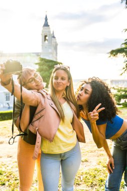 Gün batımında şehrin bakış açısında dijital kamerayla selfie çeken kadınlar başarılı oluyor.