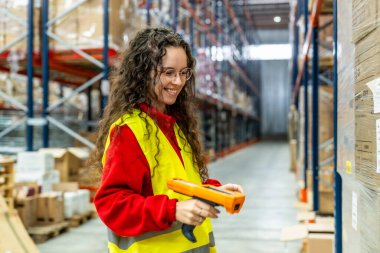 Dağıtım deposunda ürünleri tarayan mutlu genç bir kadın.