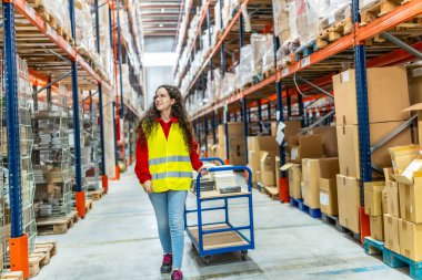 Dağıtım deposunda el arabası taşıyan genç bir kadın işçi.