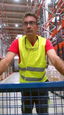 Dağıtım deposunda güvenli kıyafetler giyen olgun bir işçi.