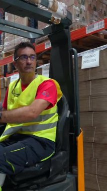 Sarı yelekli bir işçi endüstriyel bir ortamda forklift kullanıyor.