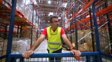 Yansıtıcı elbiseli bir adam depodaki dağıtımı kontrol ediyor.