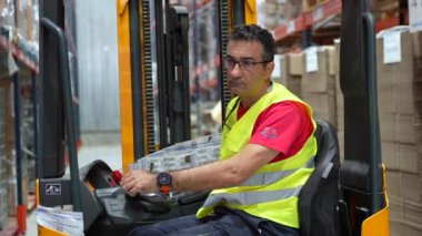 Depoda forklift kullanan olgun bir erkek işçi.