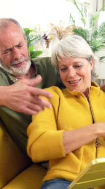 Mutlu kıdemli çiftler tatillerini evde dizüstü bilgisayarla planlıyorlar.