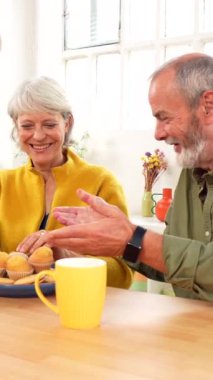 Yaşlı adam, karısı oturma odasında dijital tablet kullanırken ona kahvaltı servisi yapıyor.