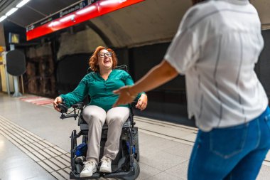 Gülümseyen engelli bir kadınla arkadaş arasında metroda mutlu bir buluşma.