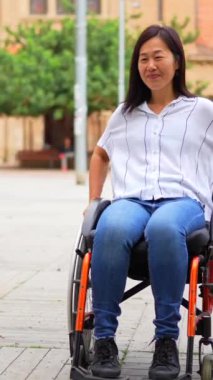 İki çoklu etnik engelli kadın tekerlekli sandalyede sokakta vedalaşıyor.