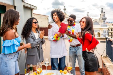 Çatı katındaki doğum günü partisini kutlayan çok ırklı arkadaşlar.