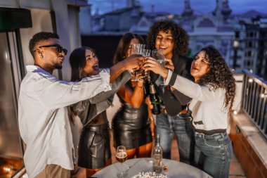 Çeşit çeşit ve mutlu çok ırklı arkadaşların tavan partisi sırasında şampanya ile kadeh kaldırışları.