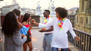 Akşam çatısı partisinde abur cubur ve içeceklerle cep telefonu kullanan çok ırklı arkadaşlar.