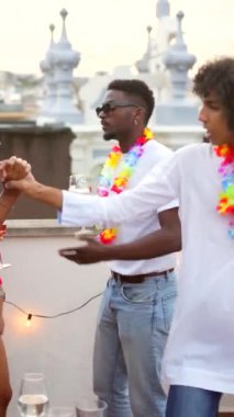 Akşam çatısı partisinde abur cubur ve içeceklerle cep telefonu kullanan çok ırklı arkadaşlar.