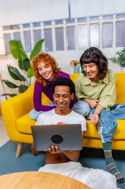 Modern bir kanepede yan yana oturan üç Lgtb çalışanının dikey fotoğrafı.