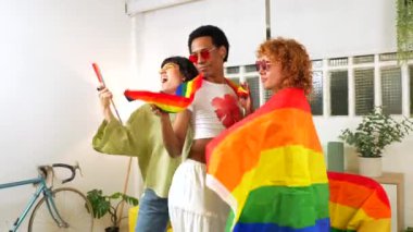 Lezbiyen kadın arkadaşlarıyla eşcinsel adam gururla dans ediyor lgbt gökkuşağı bayrağı sallıyor