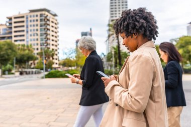 Çok ırklı iş adamlarının kentte yürürken cep telefonlarına takılıp kaldıkları yan manzara