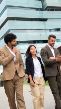 Çok ırklı iş adamları, tropikal modern bir şehirde finans bölgesinde rahatça sohbet ediyorlar.