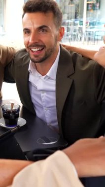 Çok ırklı iş adamları bir kafeteryada birlikte oturarak kutluyor ve kutluyorlar.