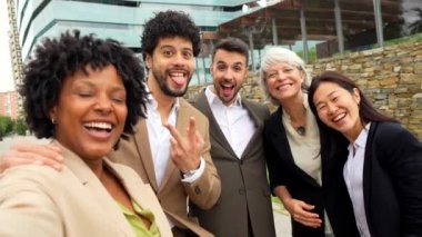 Çok ırklı iş arkadaşları şehirde selfie çekerken başarı gösteriyorlar.