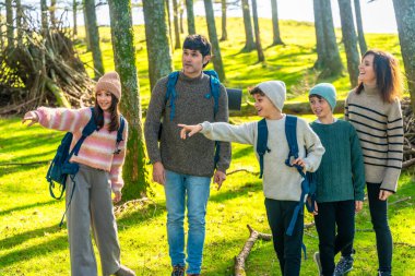 Üç çocuklu bir aile dağlık arazide yürüyüş yapıyor doğayı keşfediyor ve birlikte eğleniyorlar.