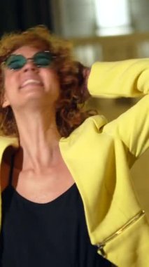 Geceleri kameraya gülümseyen güneş gözlüklü çapkın kadın şehirdeki anıtın yanında duruyor.