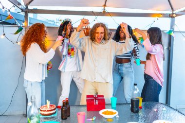 Terasta doğum günü partisini kutlayan bir grup genç çoklu etnik arkadaşın ön görüntüsü.