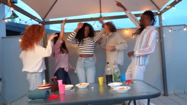 Mutlu çok ırklı arkadaş grubu terasta doğum günü partisini kutluyor.