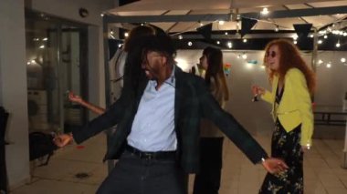 Şehirde bir terasta arkadaşlarıyla dans eden şık bir Afrikalı.