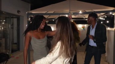 Şehvetli Afrikalı bir kadın arkadaşlarıyla bir çatı partisinde dans ediyor.