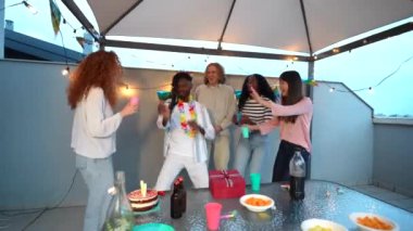 Terasta doğum günü partisini kutlayan bir grup genç çoklu etnik arkadaşın ön görüntüsü.
