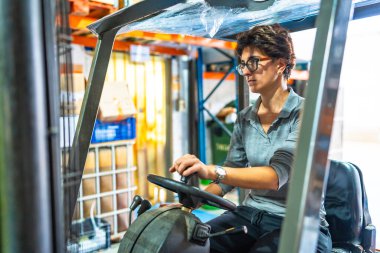 Kafkasyalı yetişkin kadın depoda forklift kullanıyor.
