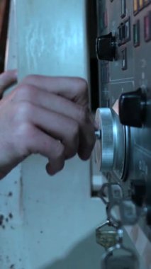 Cnc fabrikasındaki torna makinesinin kontrol panelini kullanan beyaz bir erkek işçinin ellerine yan bakış.