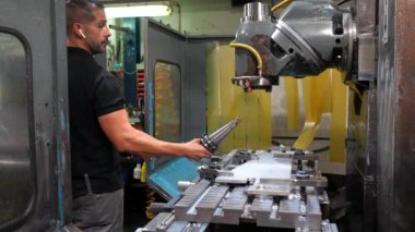Erkek operatör müzik dinliyor Cnc fabrikasında değirmen makinesiyle çalışıyor