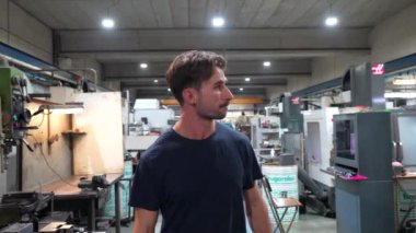 Cnc fabrikasında çalışan genç bir işçinin portresi kameraya bakıyor.