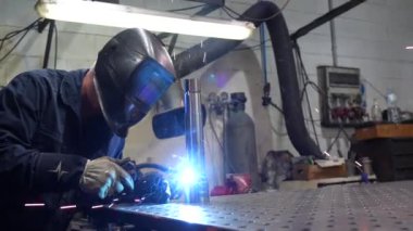 Sadece metal fabrikasında koruyucu eldiven ve maske takan konsantre bir erkek işçi.