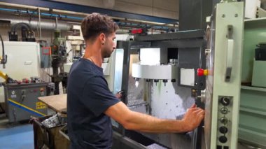 Cnc fabrikasındaki plastik parçaları şekillendirmek için mekanik makine kullanan bir adam
