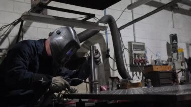 Sadece metal fabrikasında koruyucu eldiven ve maske takan konsantre bir erkek işçi.