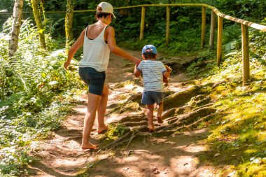 Çıplak ayaklı anne ve oğlu, Almanya 'da Kara Orman' da doğanın ve duyuların tadını çıkarmak için duyusal bir parkta yürüyorlar.