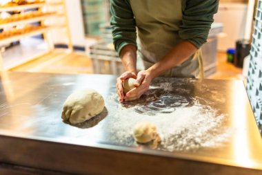 Latin bir fırının atölyesinde hamur yoğuran erkek fırıncının yakın çekimi.